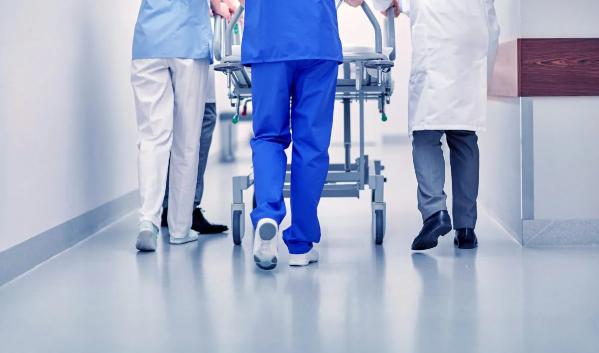 Medical staff moving a hospital gurney down a clean corridor