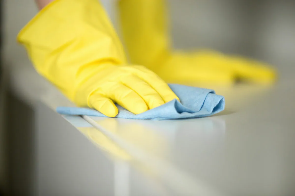 A Woods team member cleaning a surface with gloved hands